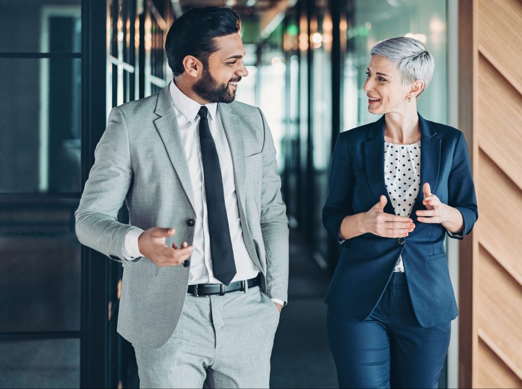 Businessman and businesswoman talking while walking side by side